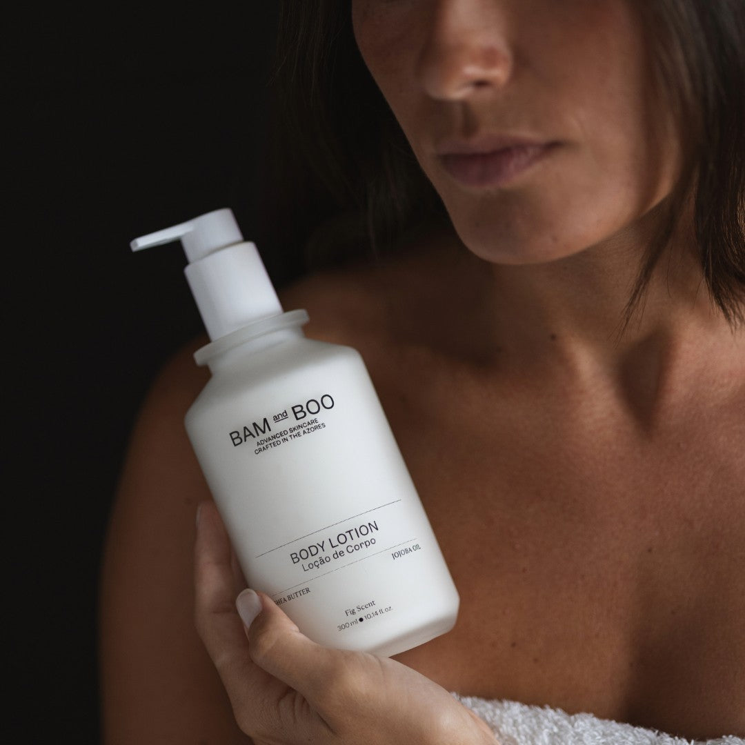 Person holding a bottle of BAM & BOO body lotion against a dark background. Vegan amenities.